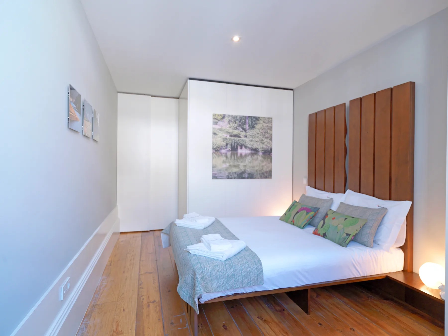 Un dormitorio con una cama bien hecha y suelo de madera.