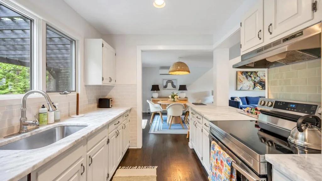 A bright kitchen with a central island and a dining area beyond.