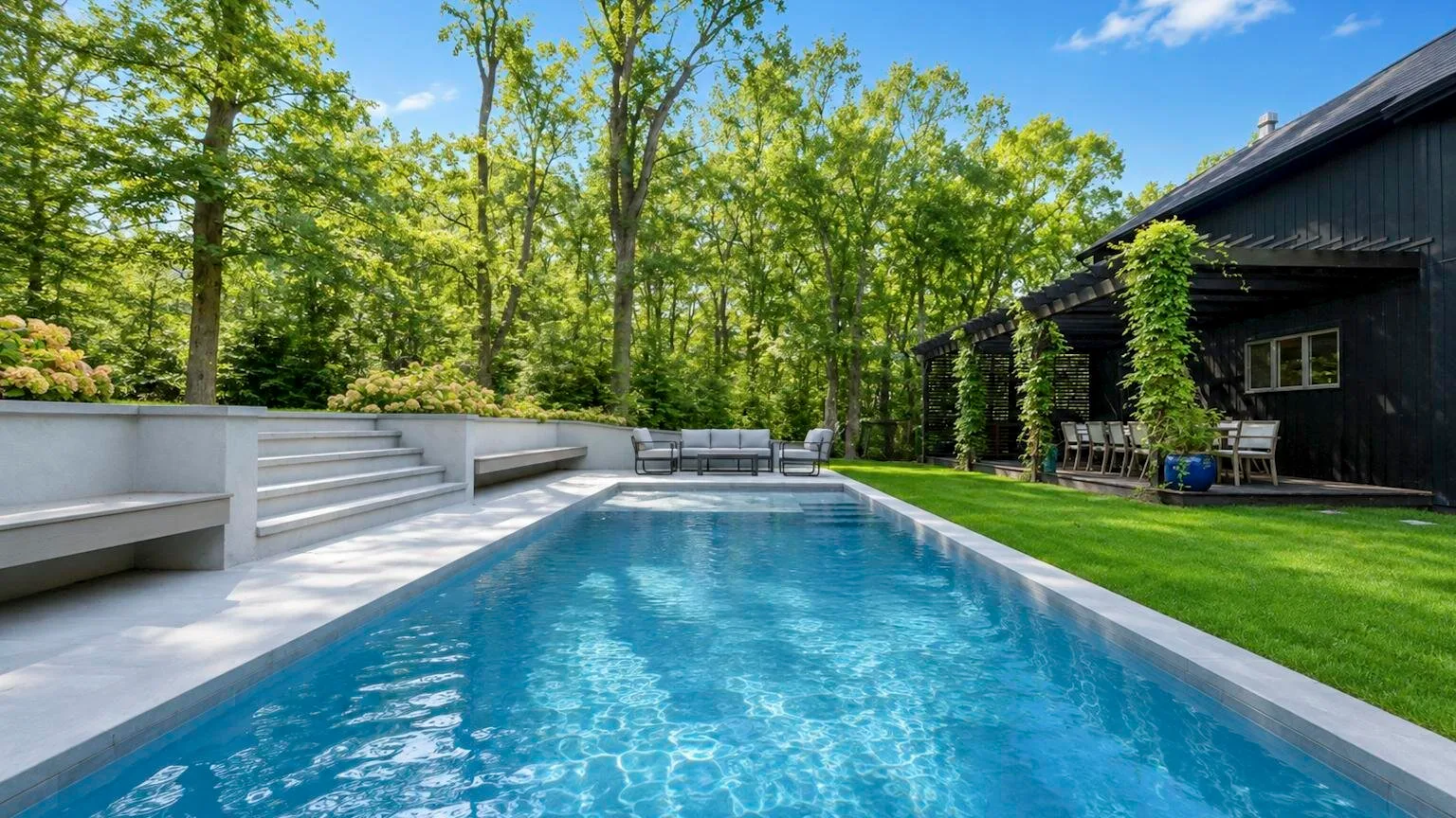 A swimming pool sits beside a dark building, with trees surrounding the outdoor area.