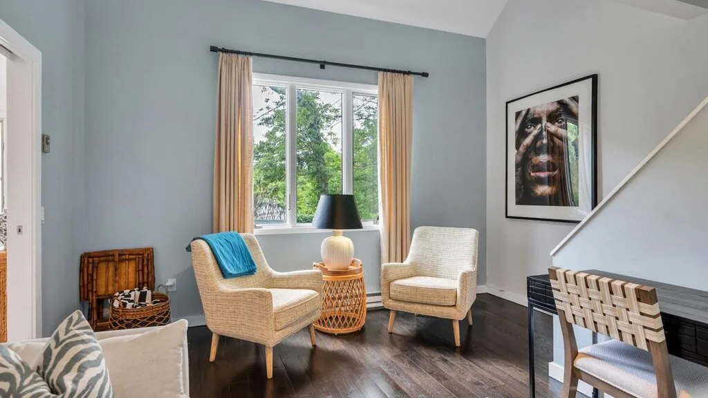 A bright living room with seating arranged around a small wicker table by the window.