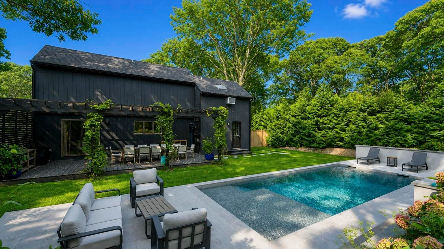 Una piscina junto a una zona de estar al aire libre y una casa oscura.