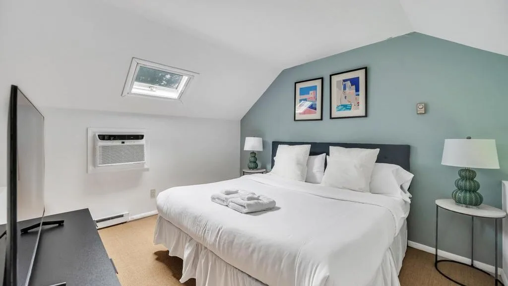 A bedroom with a large bed, framed artwork, and bedside tables.