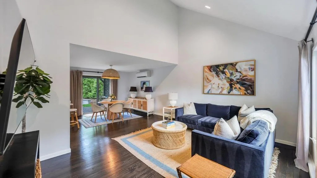 A bright living room with a blue sectional and a round coffee table.