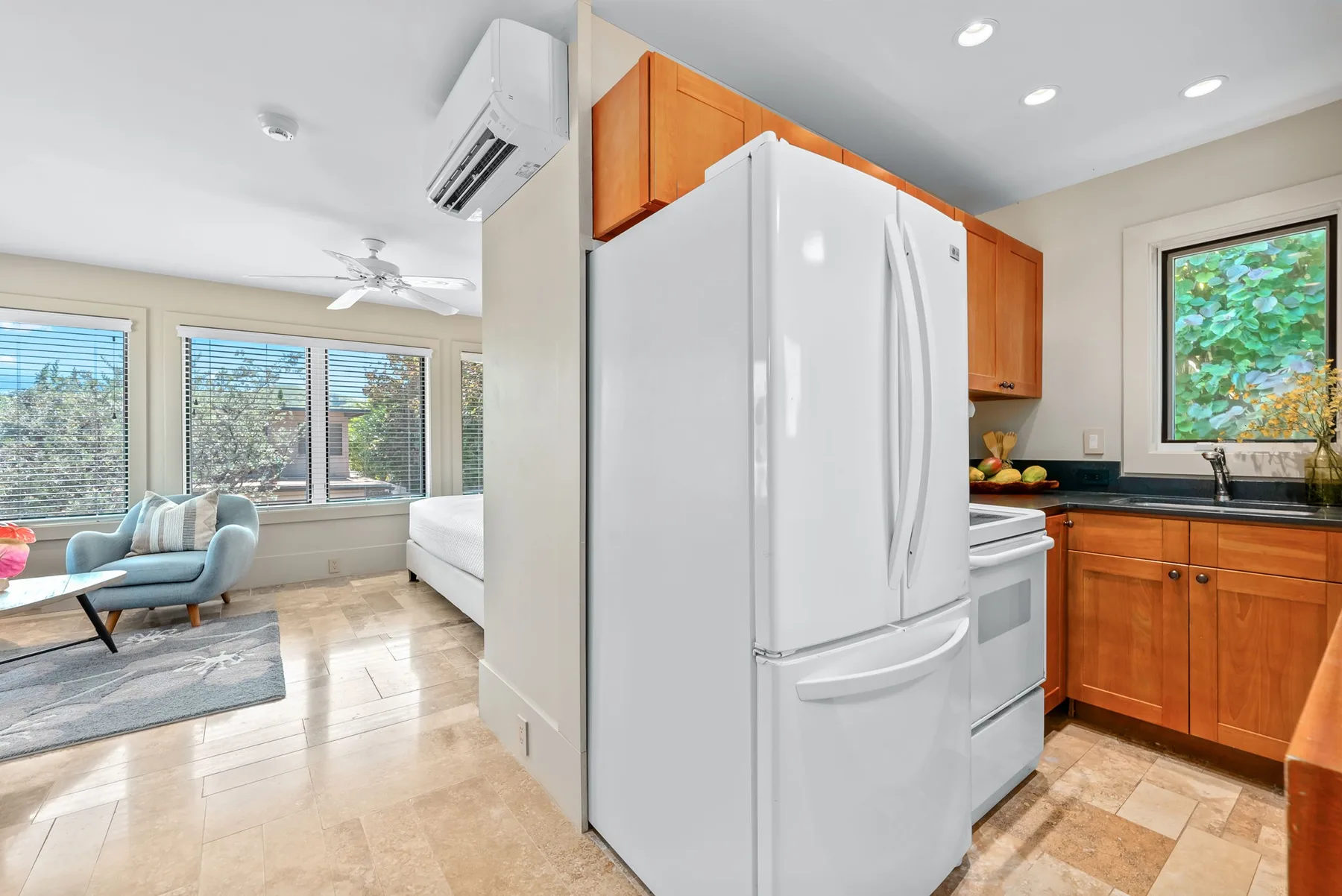 A bright kitchen with wooden cabinets and a large white refrigerator.