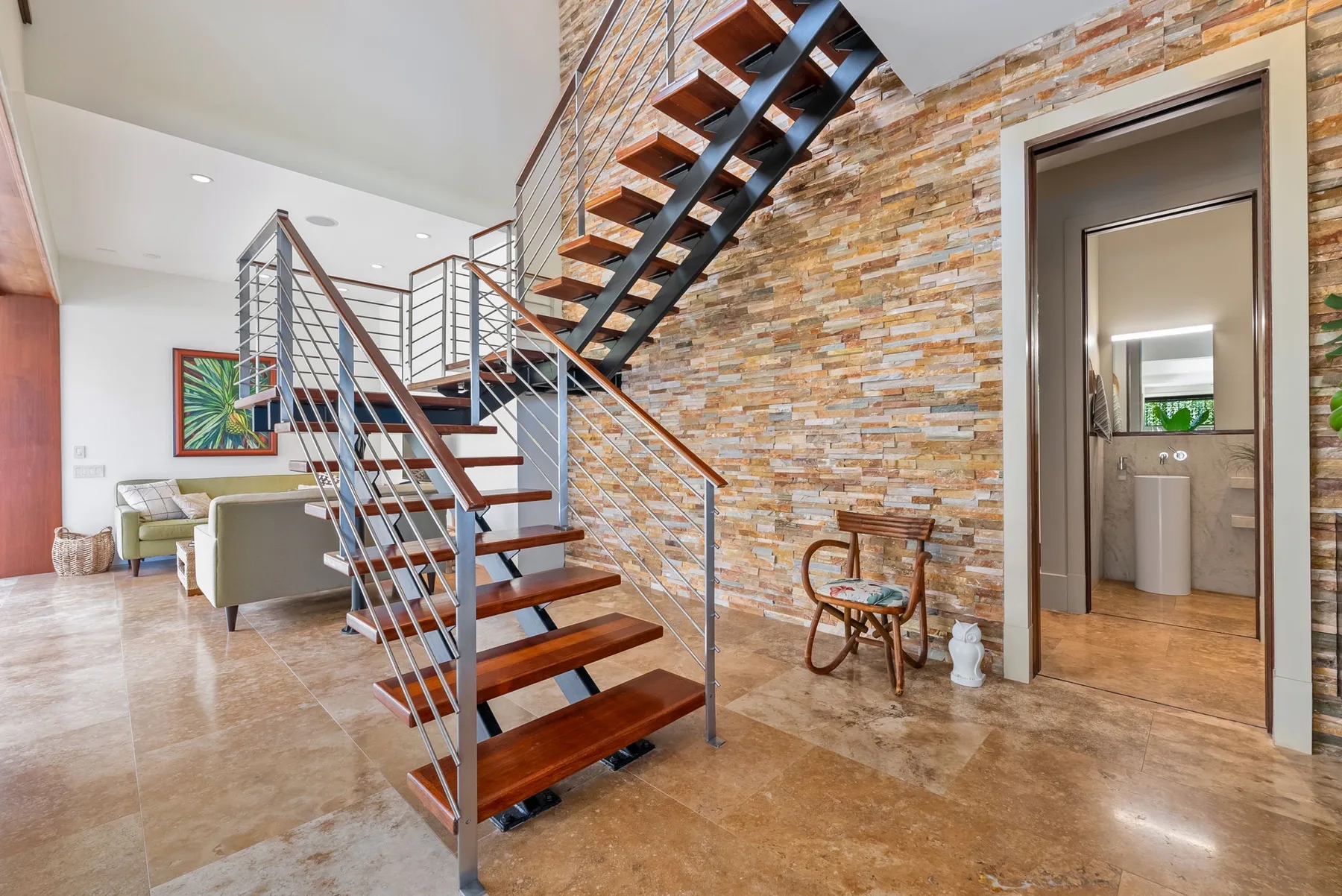 A bright interior with an open staircase and a seating area beyond.
