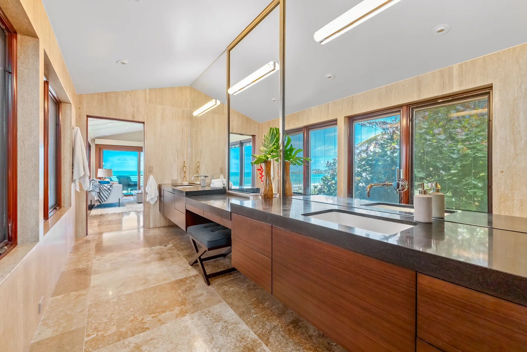 A bright bathroom features a long vanity and large windows.