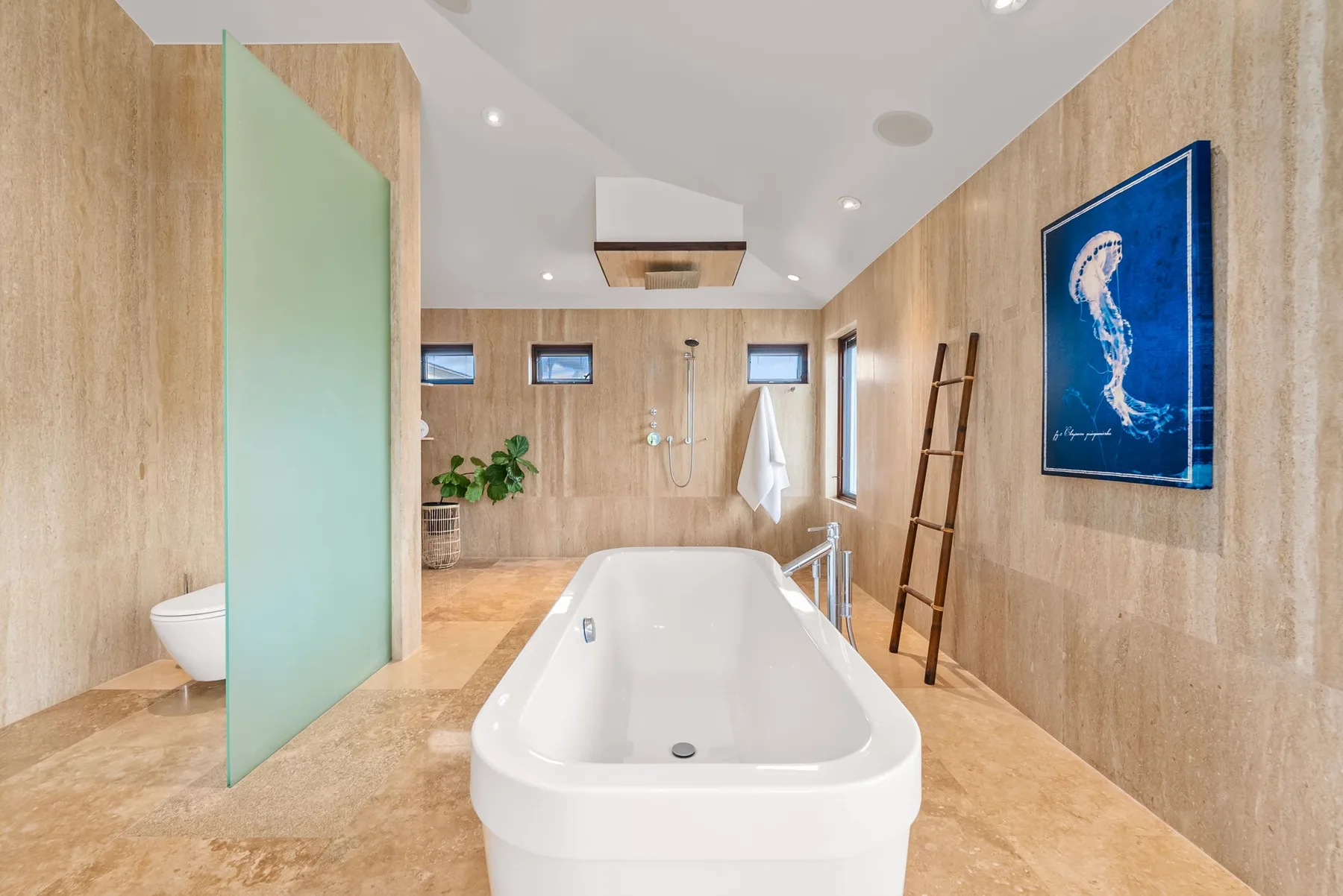 A spacious bathroom features a freestanding bathtub and a glass shower screen.