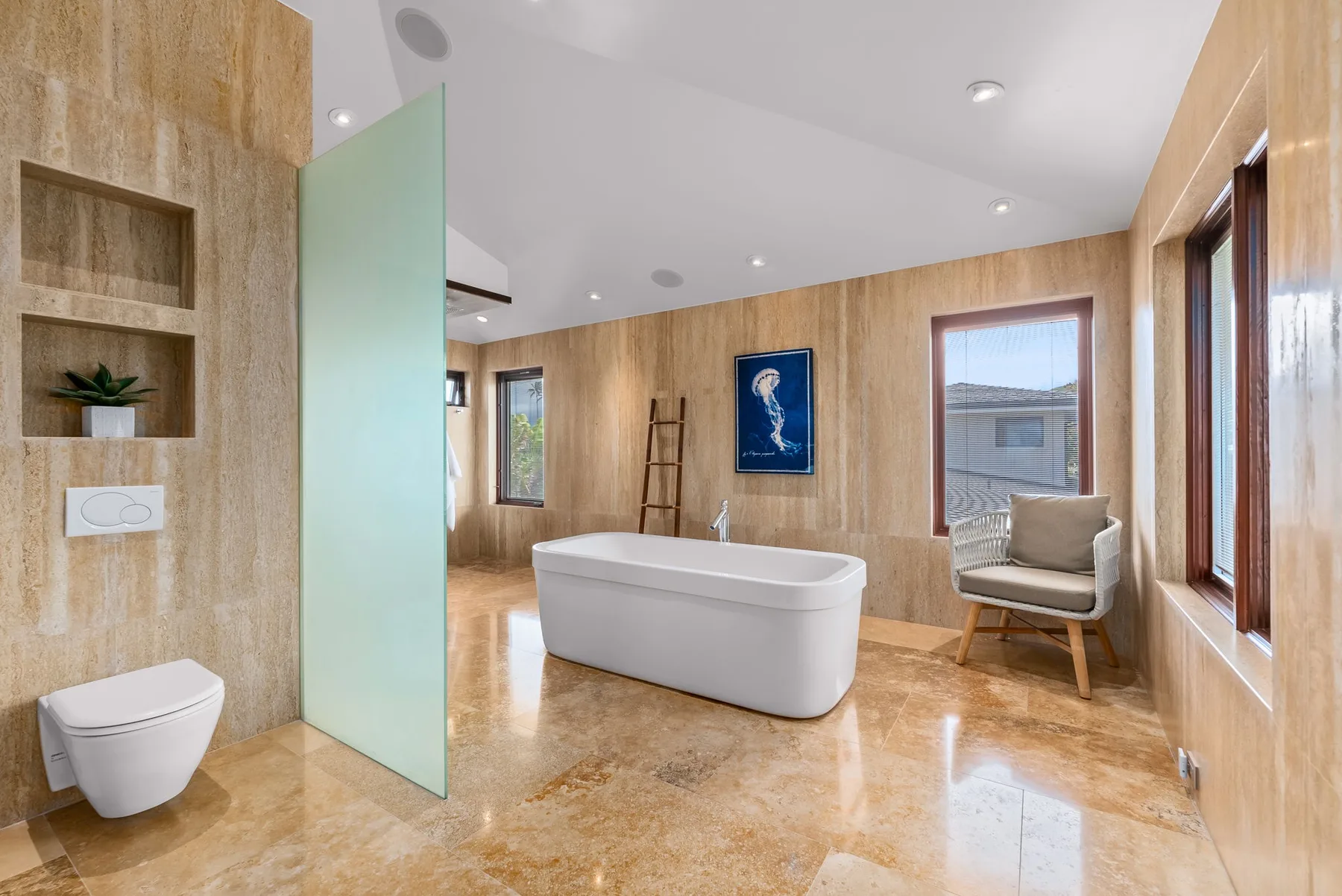 A bright bathroom with a freestanding bathtub and large windows.