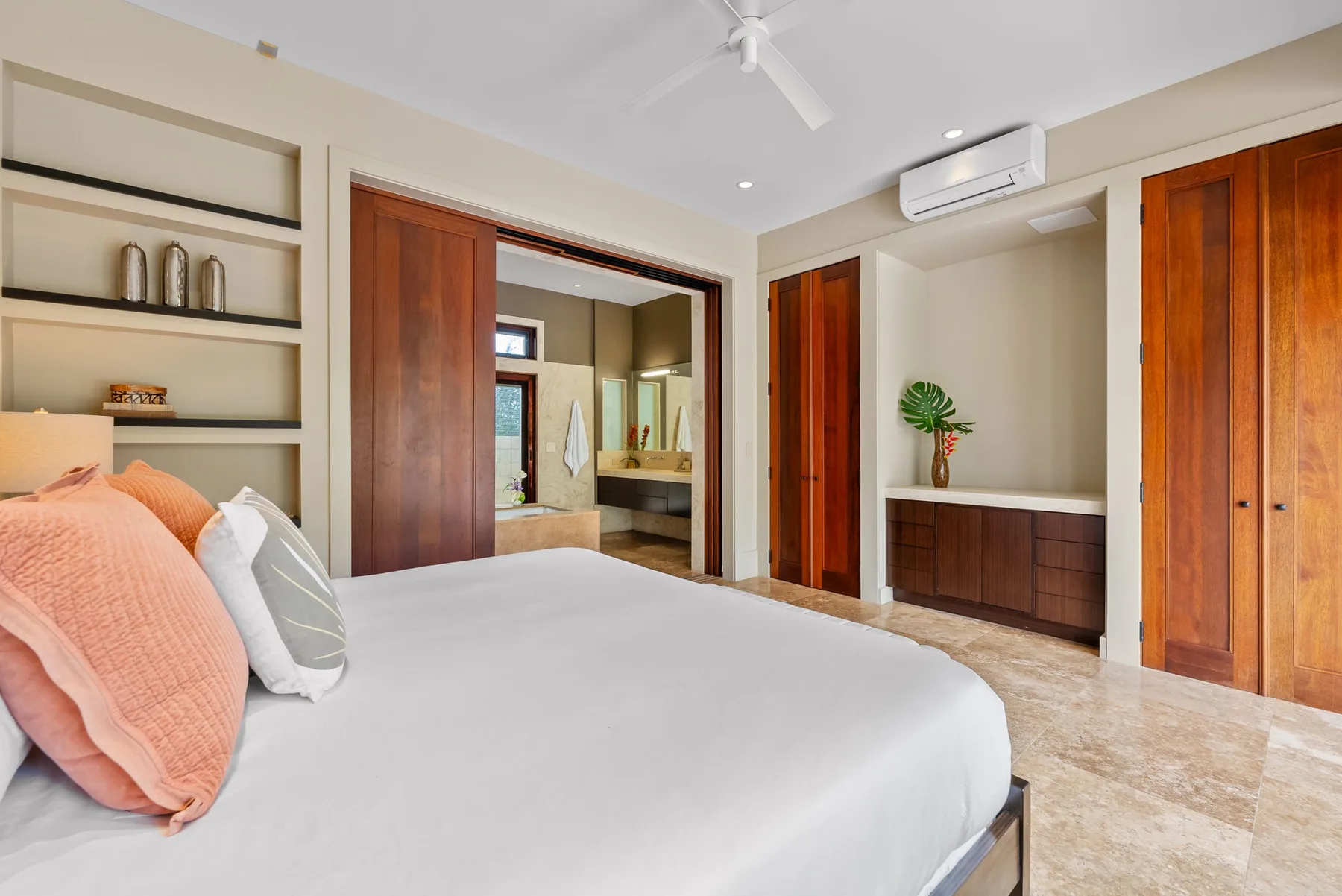 A bedroom with a large bed, built-in shelving, and wooden doors.