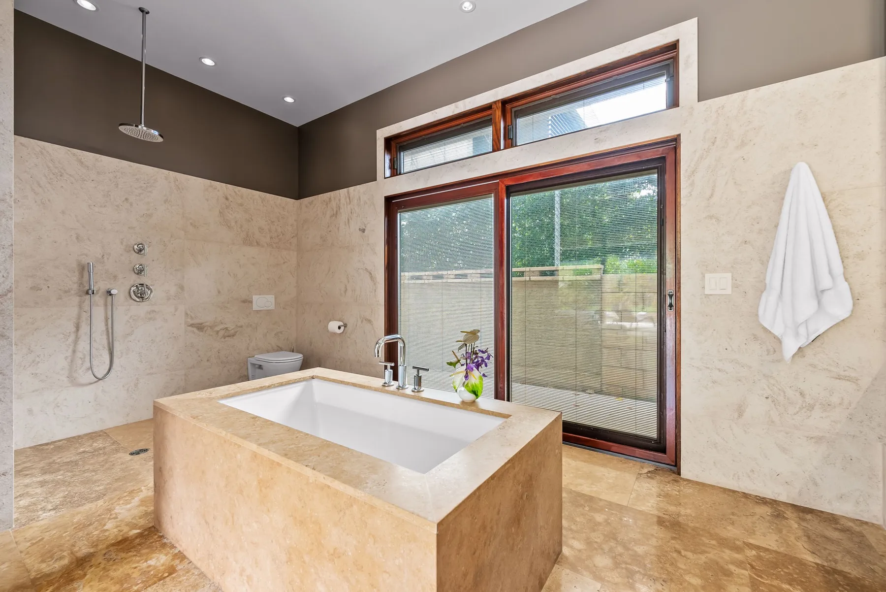 A spacious bathroom features a freestanding bathtub beside a glass door and window.
