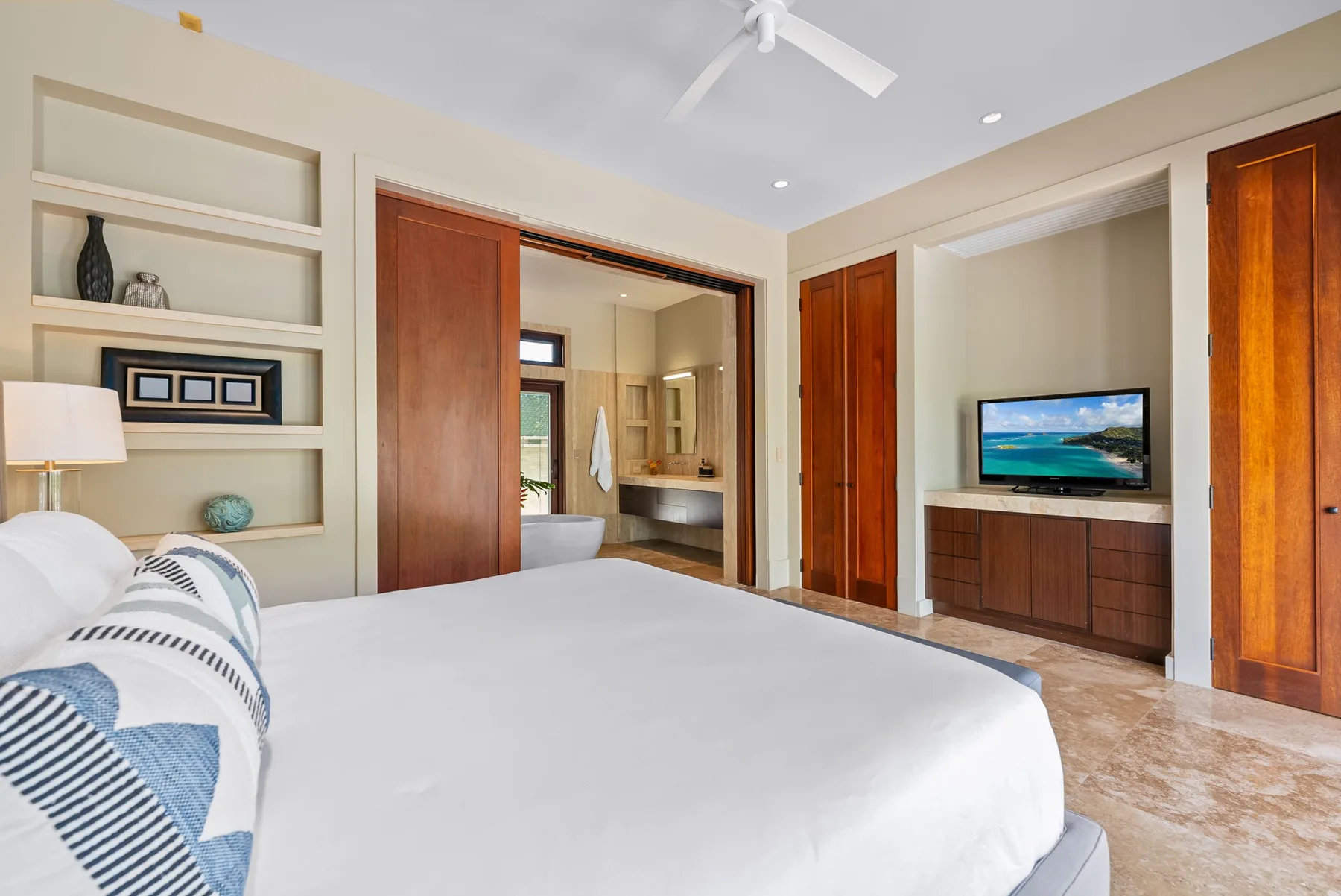 A bedroom with a large bed, built-in shelving, and a television.