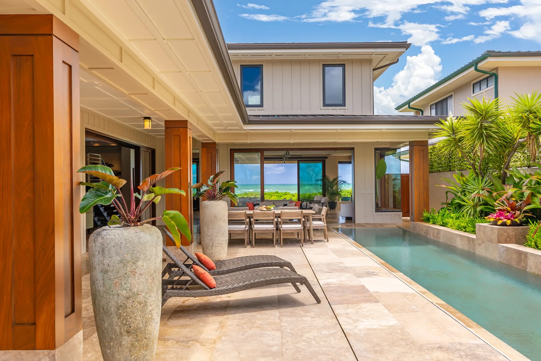 A covered patio with lounge seating and a pool beside the house.