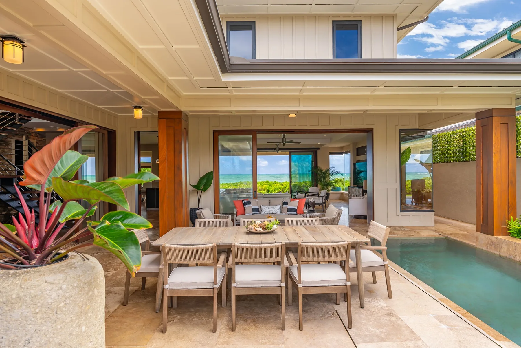A covered outdoor dining area overlooks a pool and ocean views.