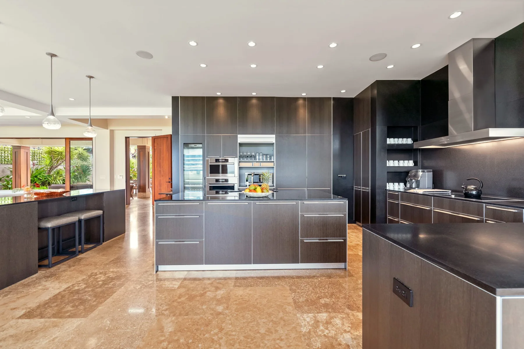 A modern kitchen with dark cabinetry, a central island, and an open dining counter.