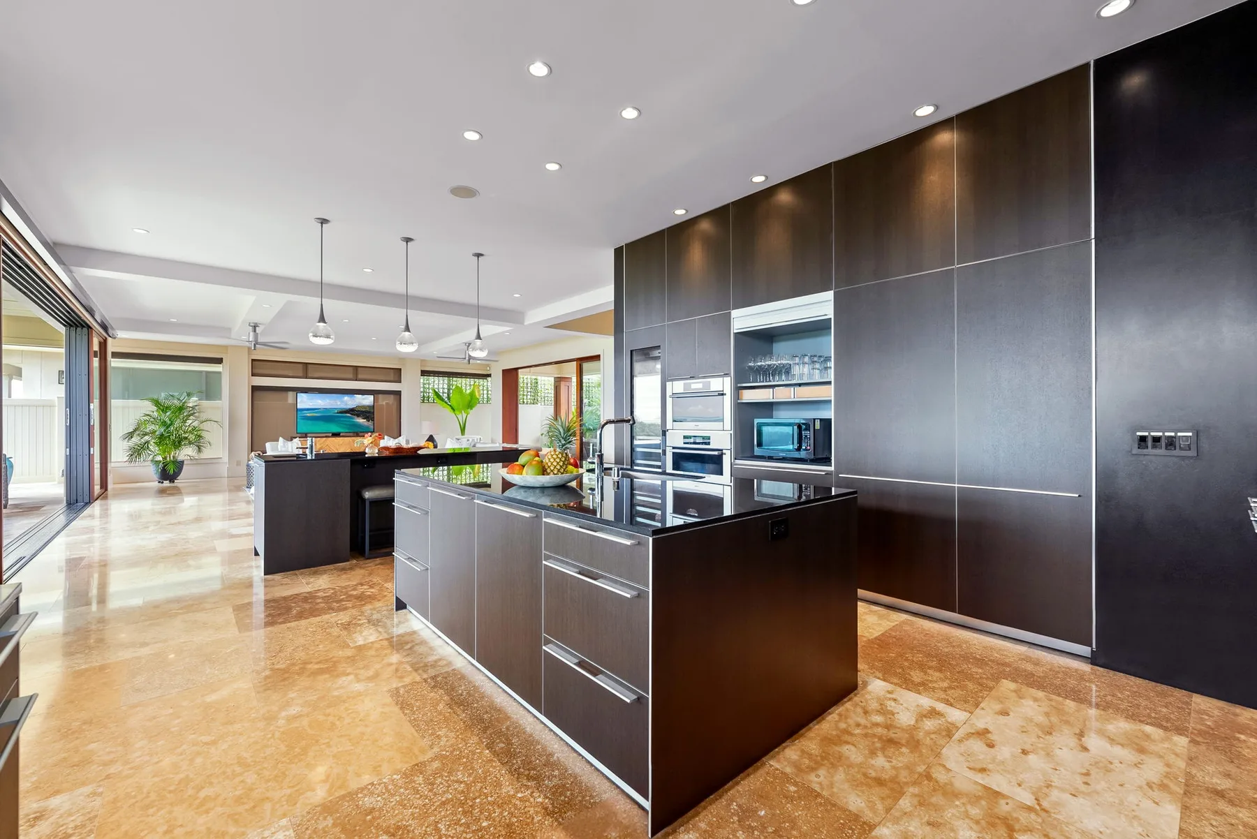 A modern kitchen with a large island and dark built-in cabinetry.
