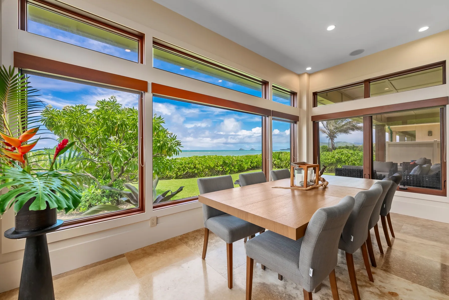 Comedor con mesa de madera y amplios ventanales con vistas a la vegetación.