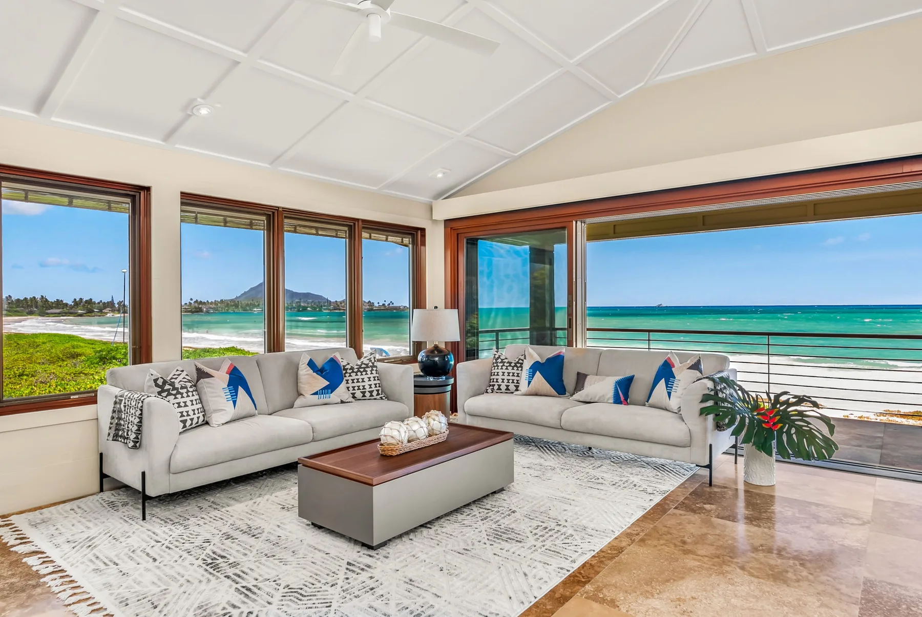 A bright living room with seating and large windows overlooking the ocean.