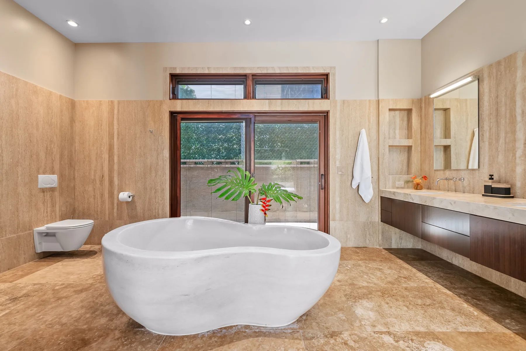 A spacious bathroom features a freestanding bathtub and a large window.