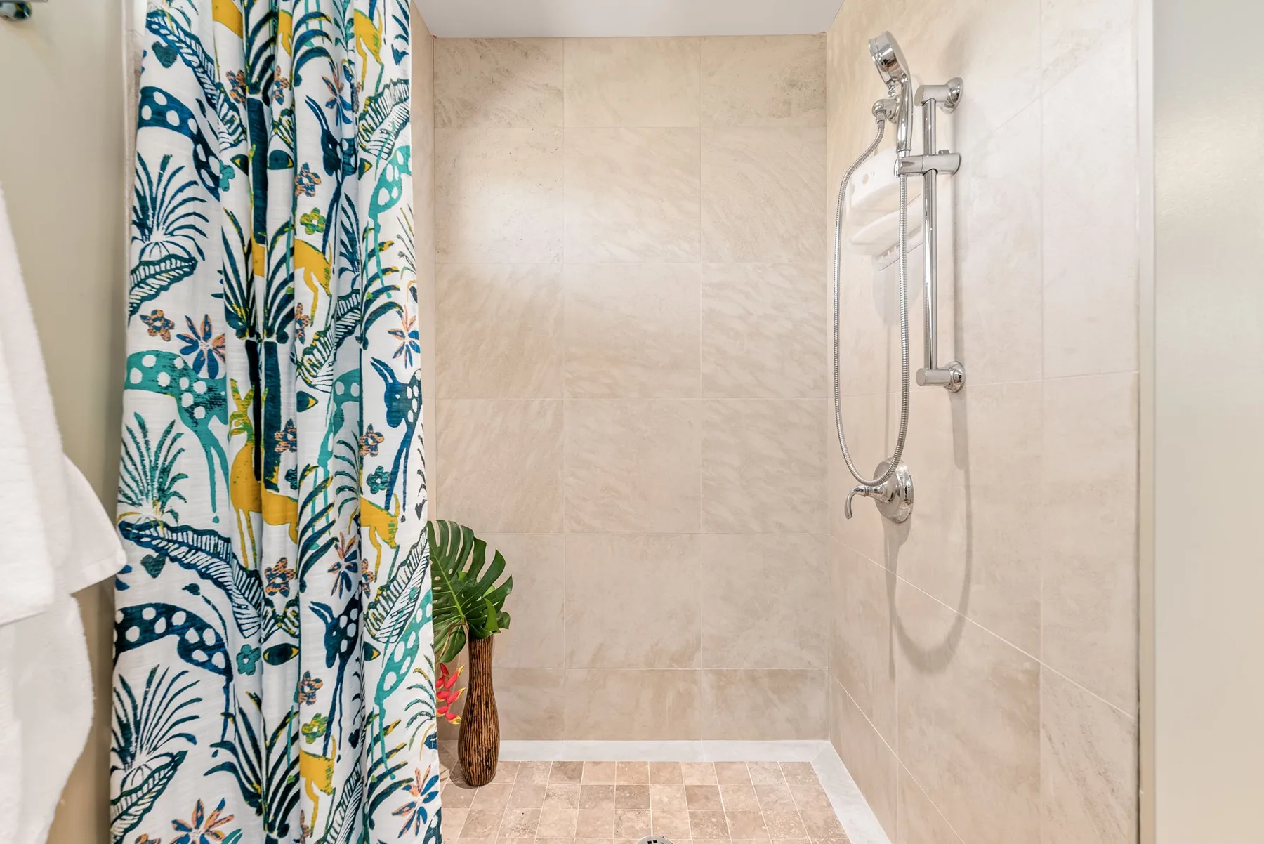 A tiled bathroom shower with a patterned curtain and wall-mounted showerhead.