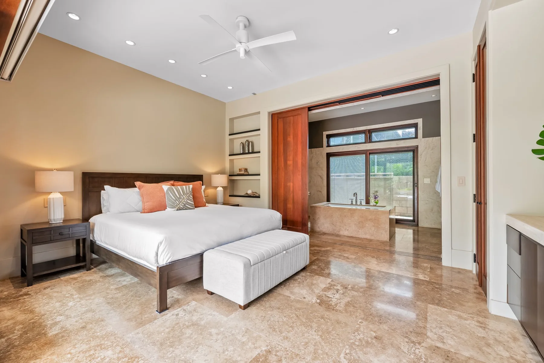 A bedroom with a neatly made bed and an adjoining bathroom area.