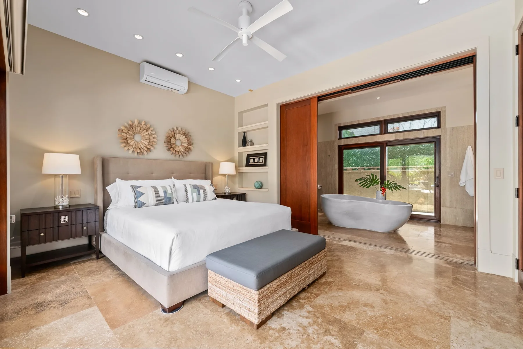 A bedroom with a large bed and an adjoining bathroom with a freestanding tub.