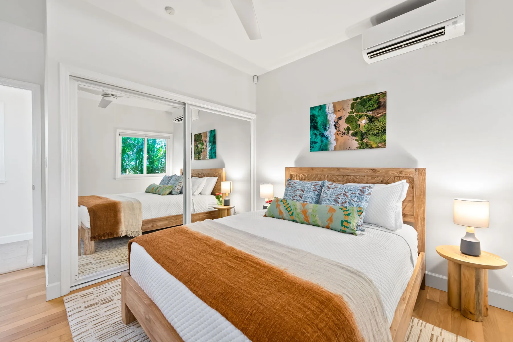 Un dormitorio luminoso con una cama de madera y puertas de armario espejadas.