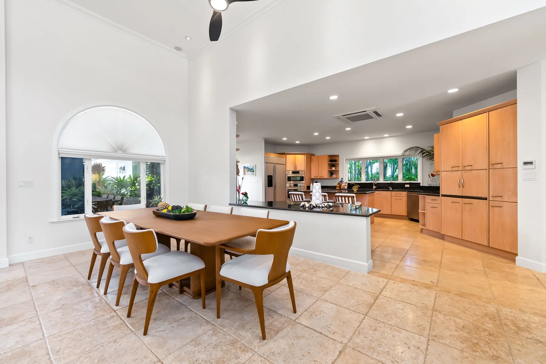 Un comedor abierto da paso a una cocina, con una mesa de madera y sillas.