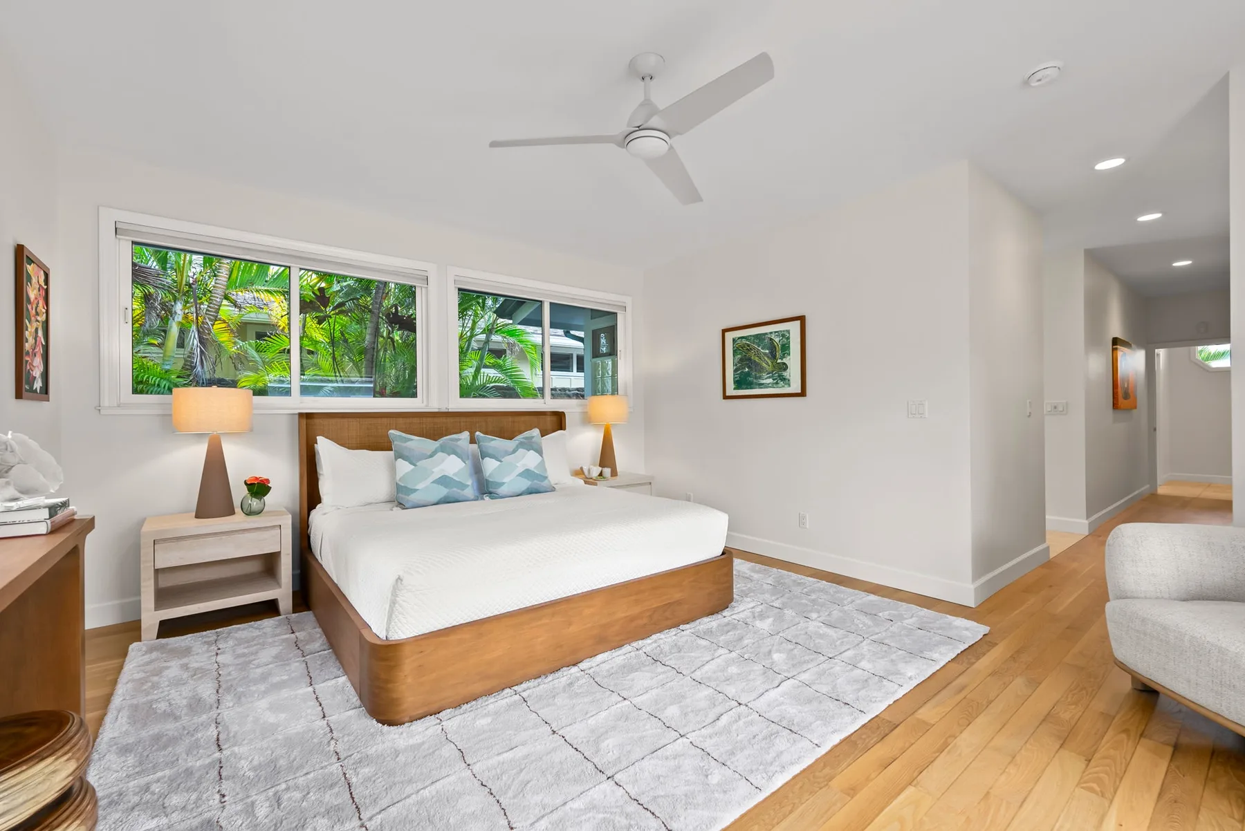 Un dormitorio luminoso con una cama bajo amplias ventanas que dan a la vegetación.