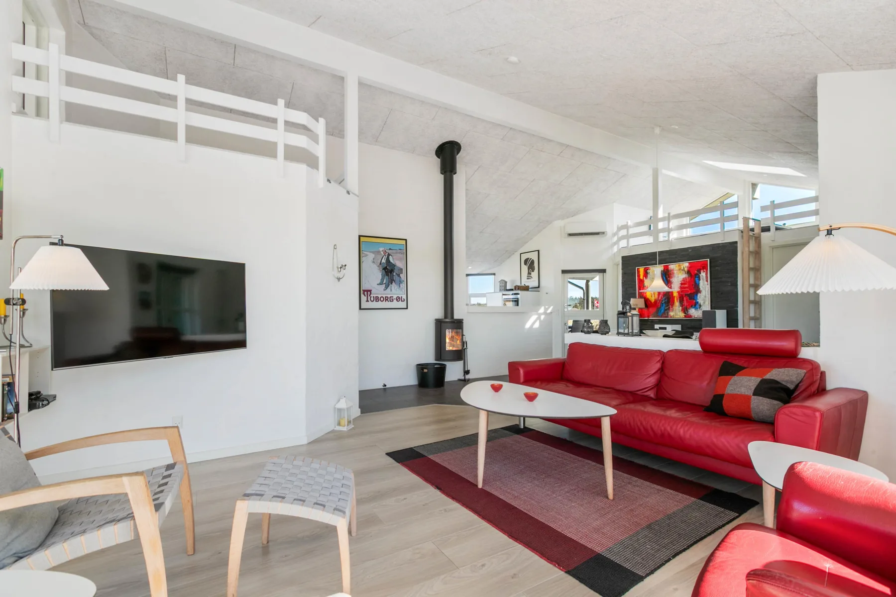 A bright living room with red seating and a television mounted on the wall.