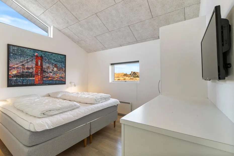 A bedroom with two beds, wall art, and a television.