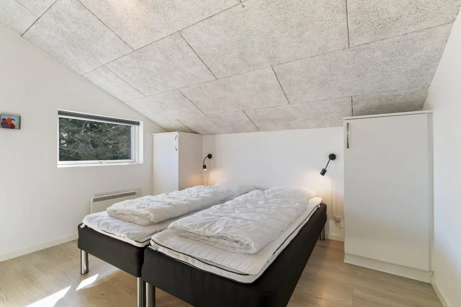 Bedroom with two beds, a window, and a sloped ceiling.