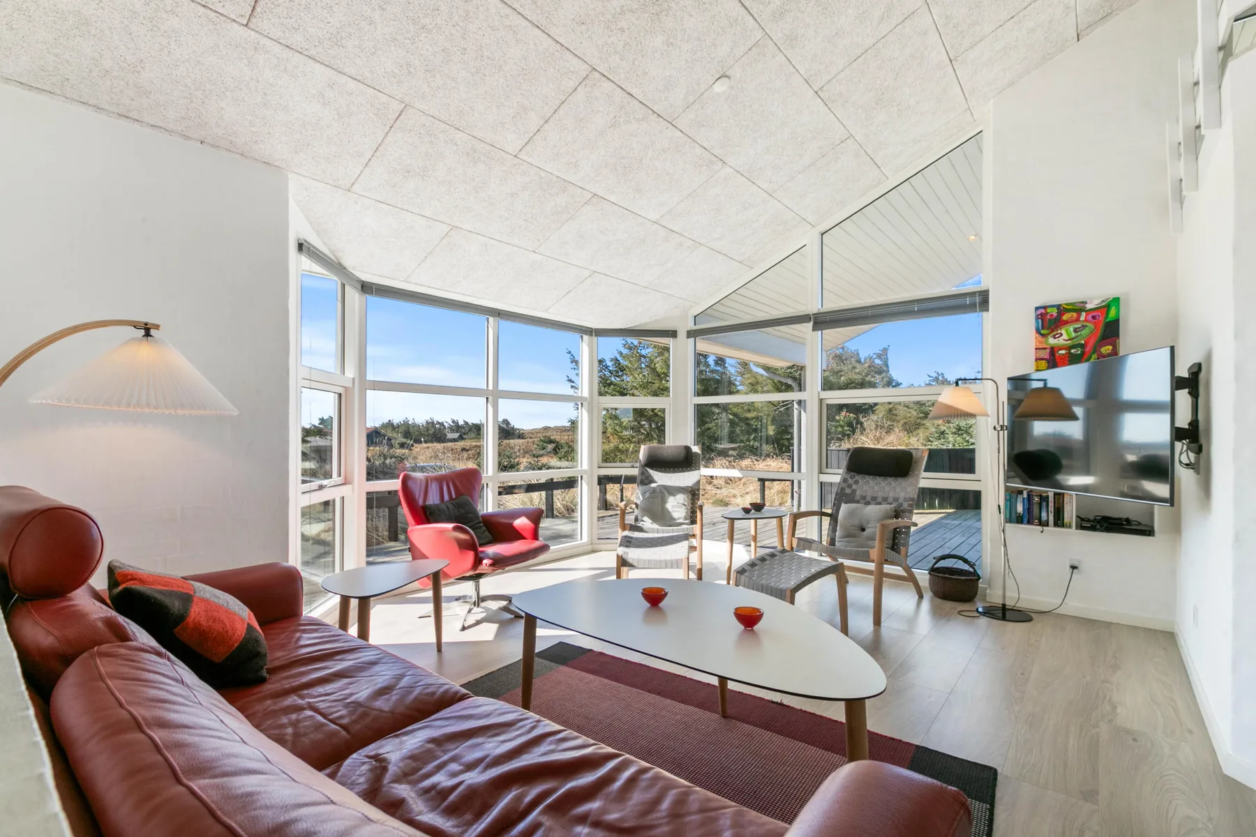 A bright living room with large windows, seating, and a television.