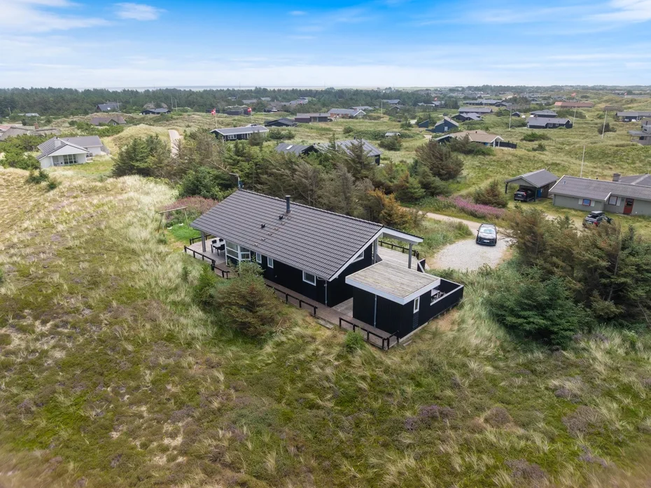 Aerial view of a dark house amid grassy terrain and scattered homes.