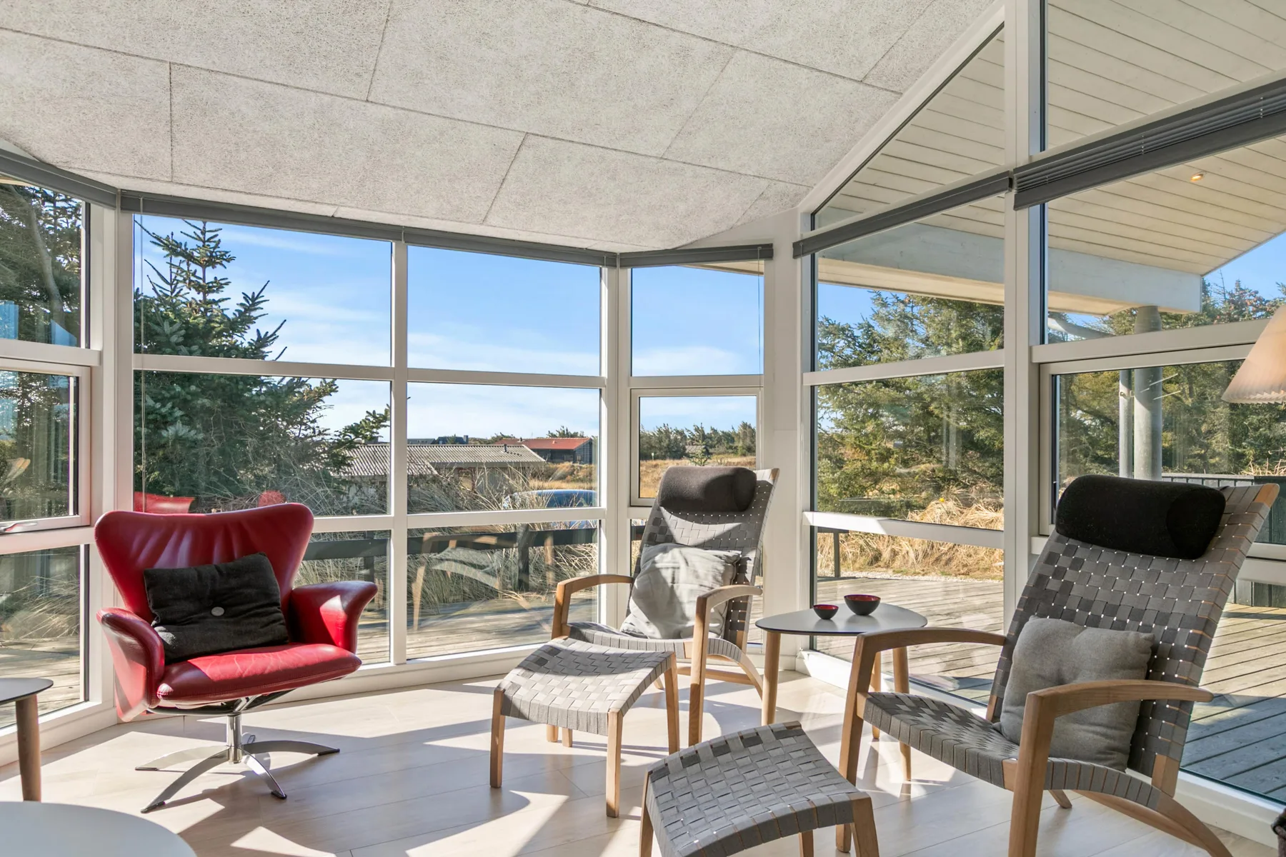 A bright sunroom with large windows and several lounge seats.