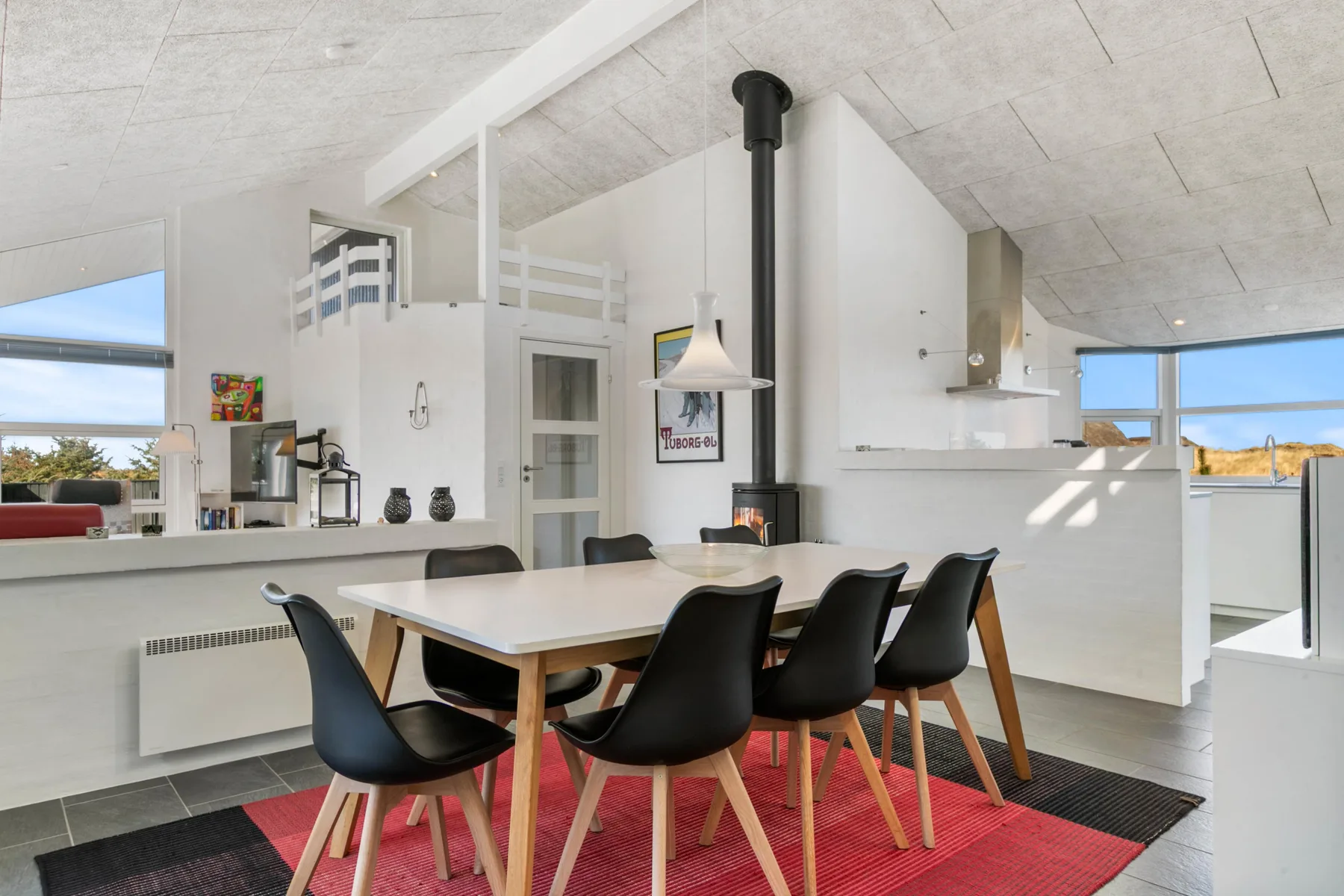 An open-plan dining area with a long table and black seating beside the kitchen.