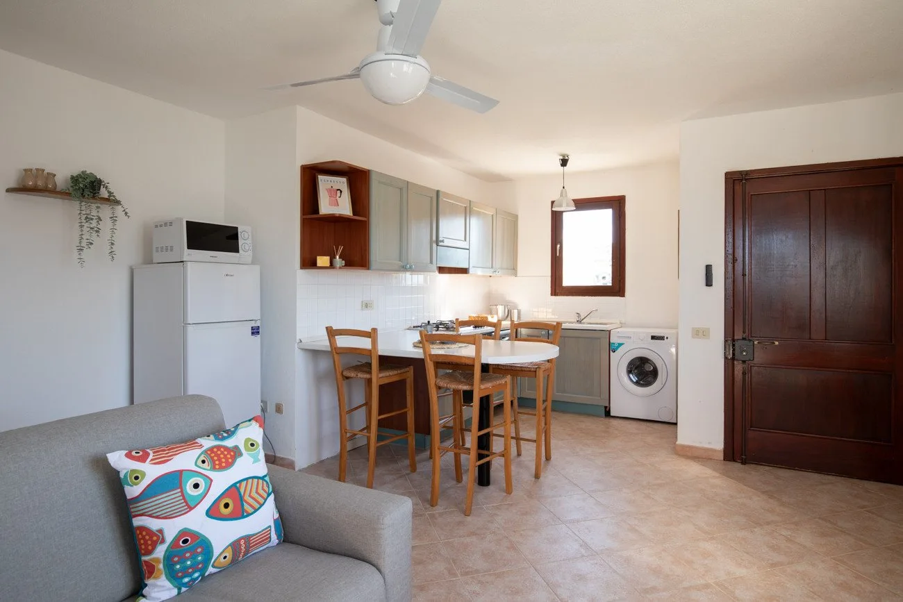 A dining and kitchen area with a table, seating, and a refrigerator.