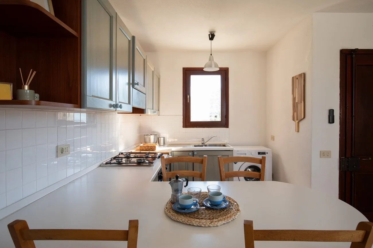 A bright kitchen with a countertop, stovetop, and dining table.