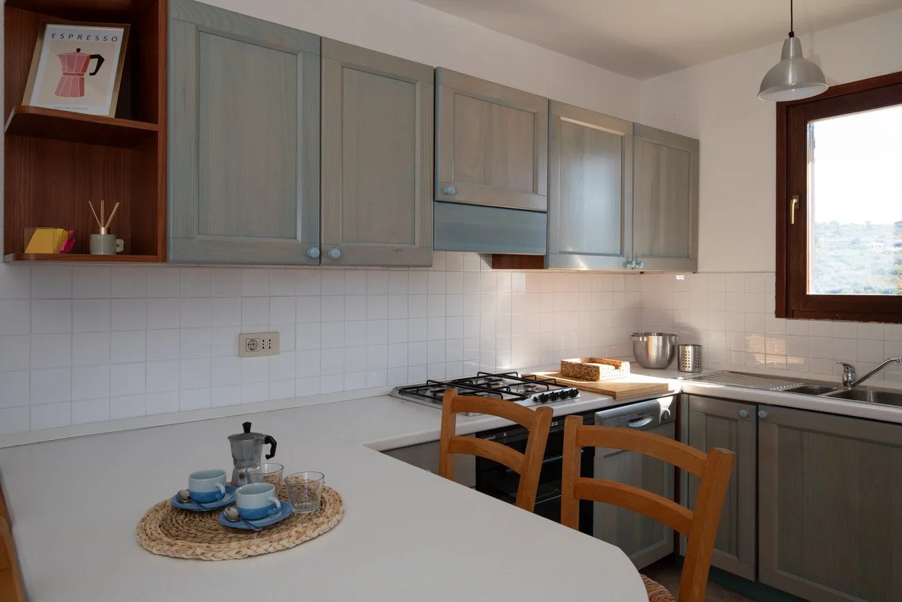 A kitchen with gray cabinets, a cooktop, and a dining table.
