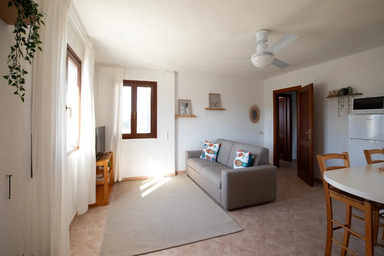 A bright living area with a gray sofa and dining table beside the kitchen.