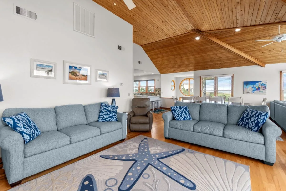 Una sala de estar luminosa con asientos grises bajo un techo de madera.