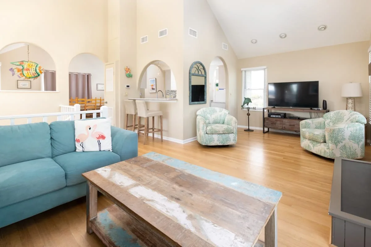An open living area has blue seating, a wooden coffee table, and a television.