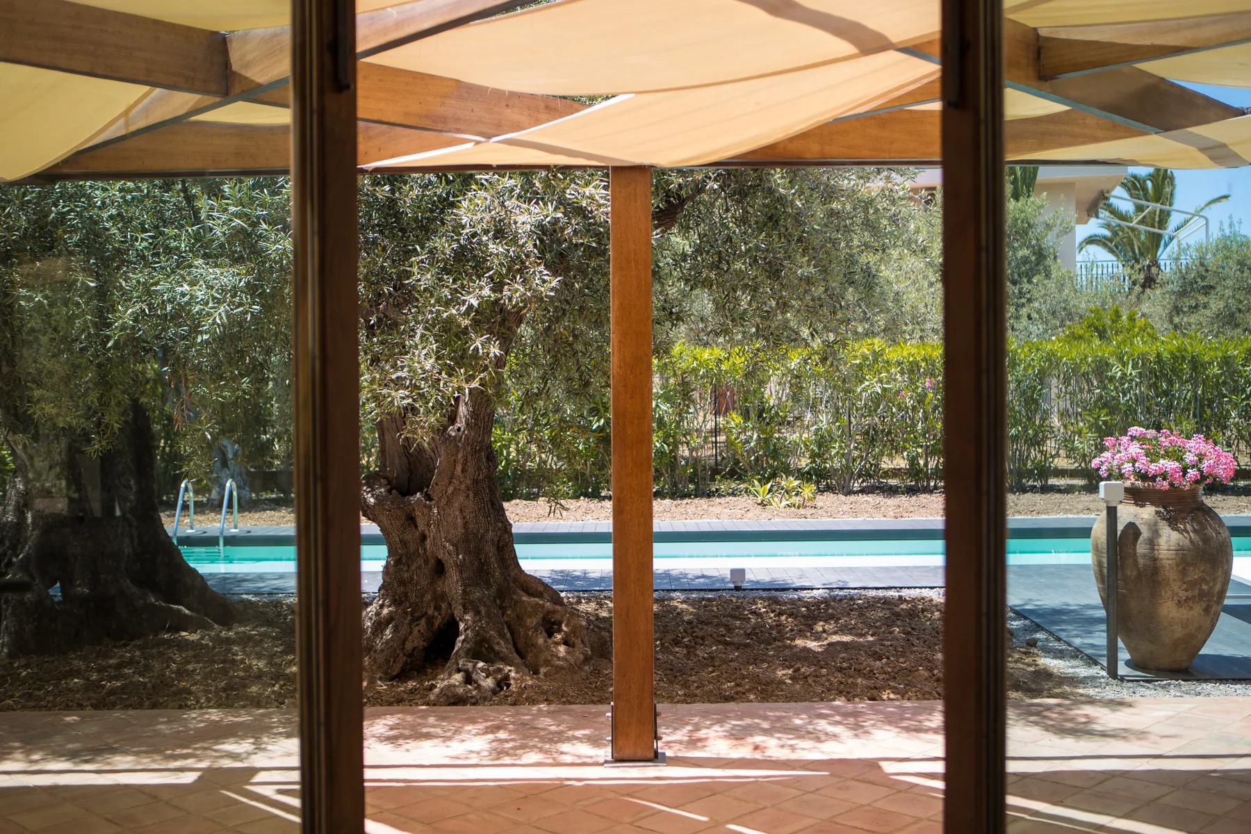 Un patio sombreado da a una piscina y un jardín frondoso.