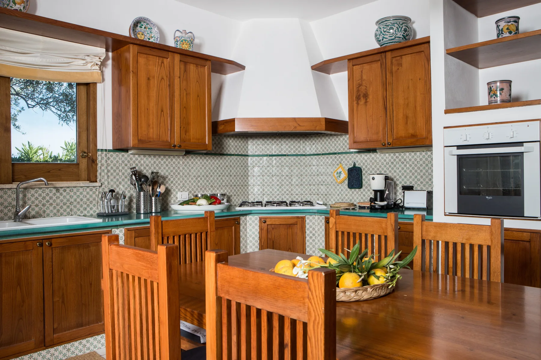 Una cocina con gabinetes de madera, encimeras y una mesa de comedor con sillas.