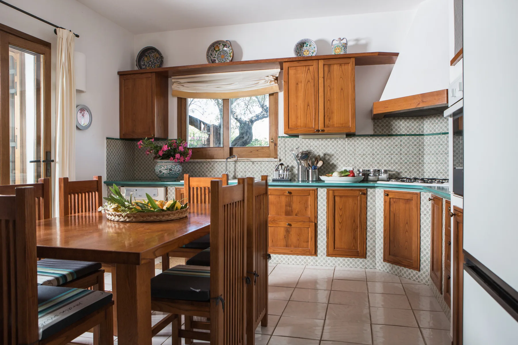 Una cocina con gabinetes de madera y una mesa de comedor con un frutero.