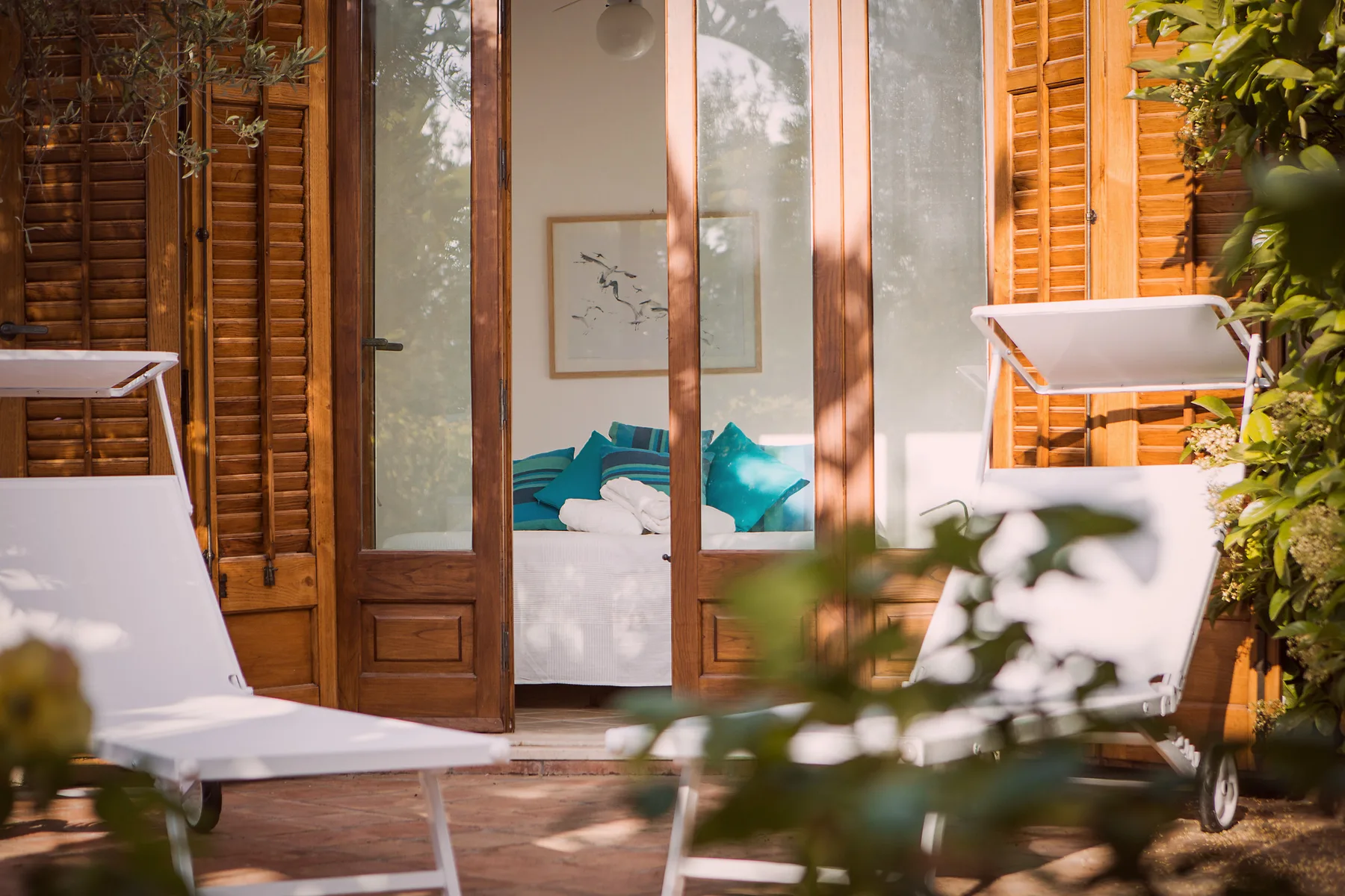 Un dormitorio se abre a un patio con asientos reclinables y contraventanas de madera.