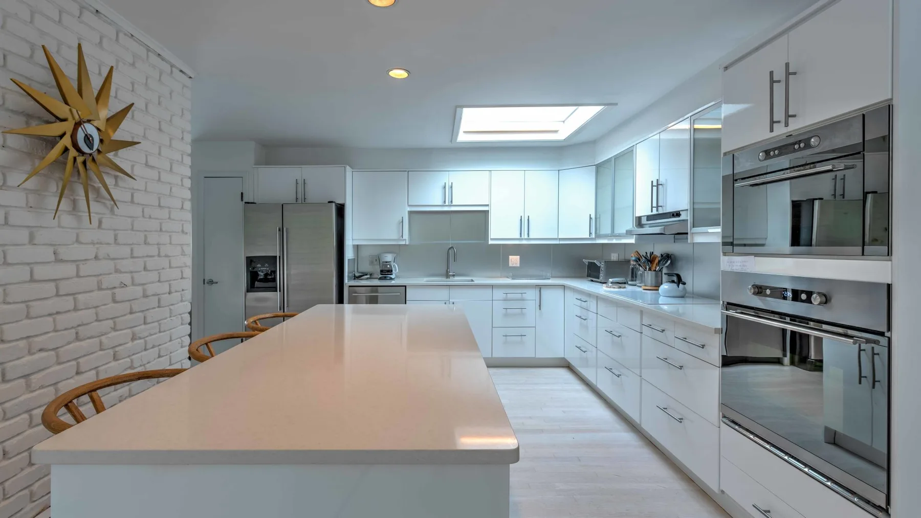 A bright kitchen with white cabinets and a long central island.