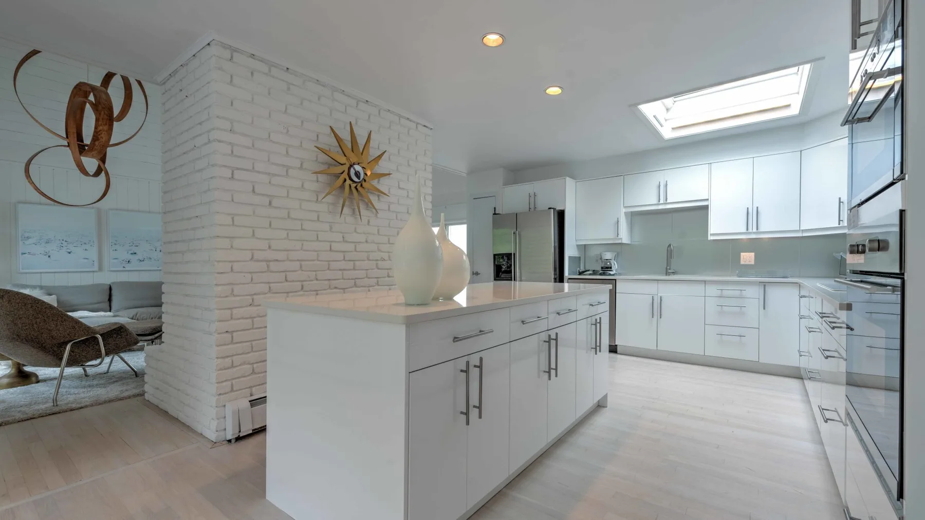 A bright modern kitchen with a central island and white cabinetry.