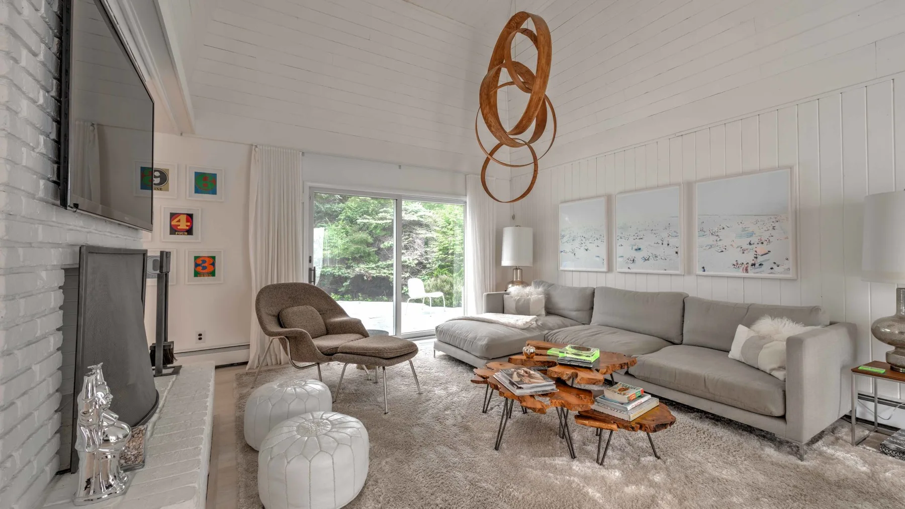 A bright living room with a gray seating area and a sliding glass door.