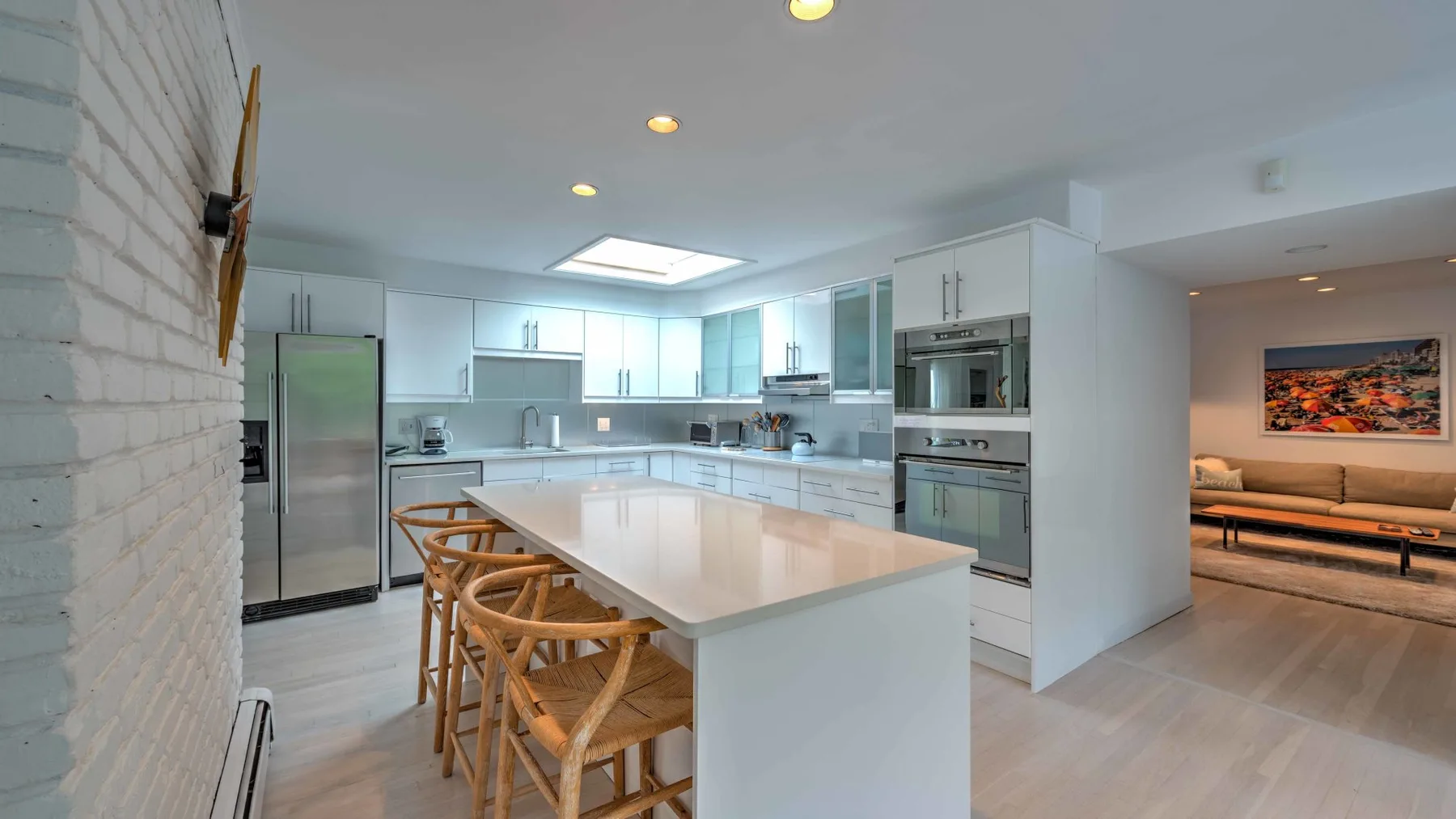 A modern kitchen with a large island and wooden seating.