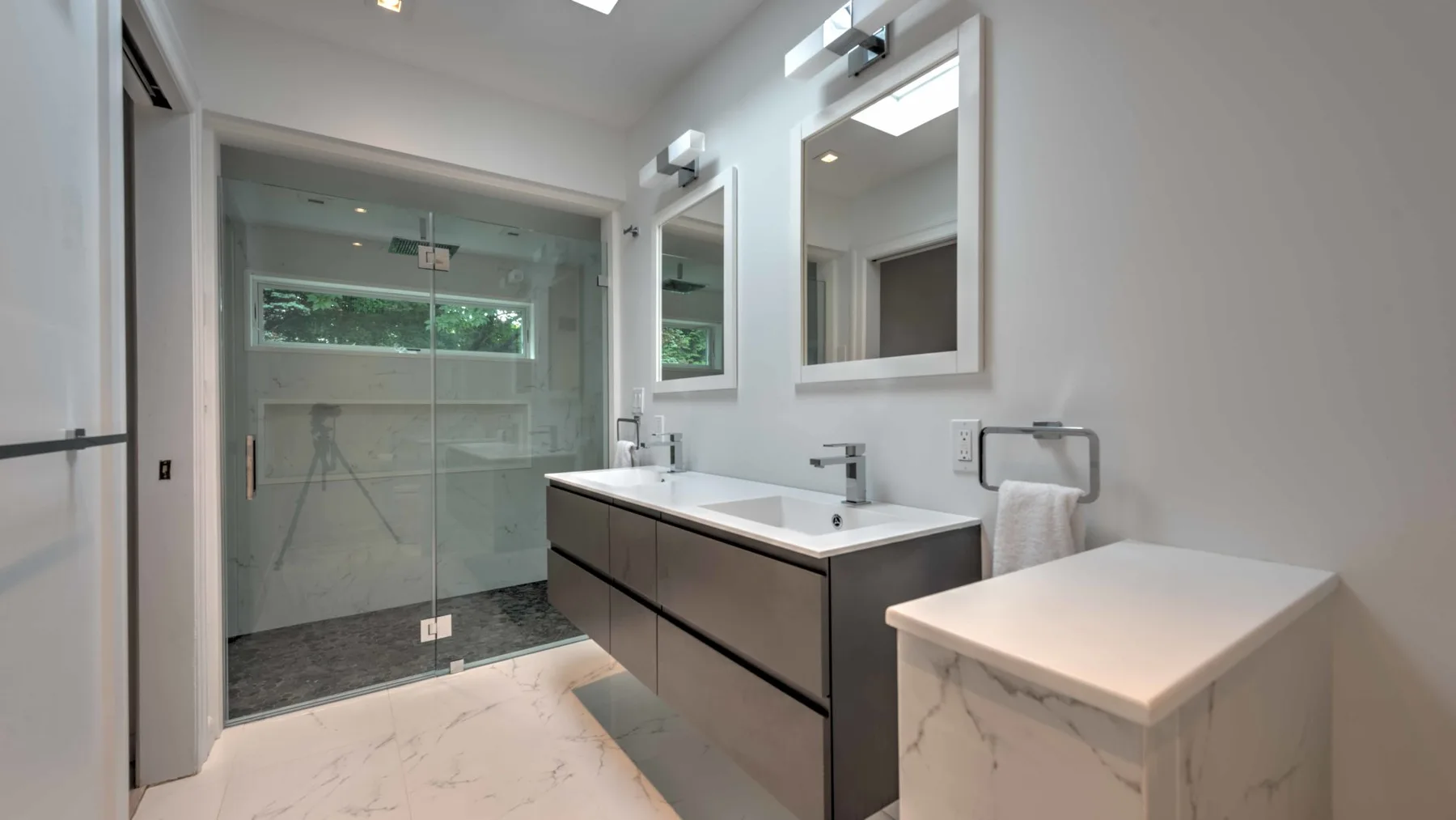 A bright modern bathroom with a glass shower and a wide vanity.